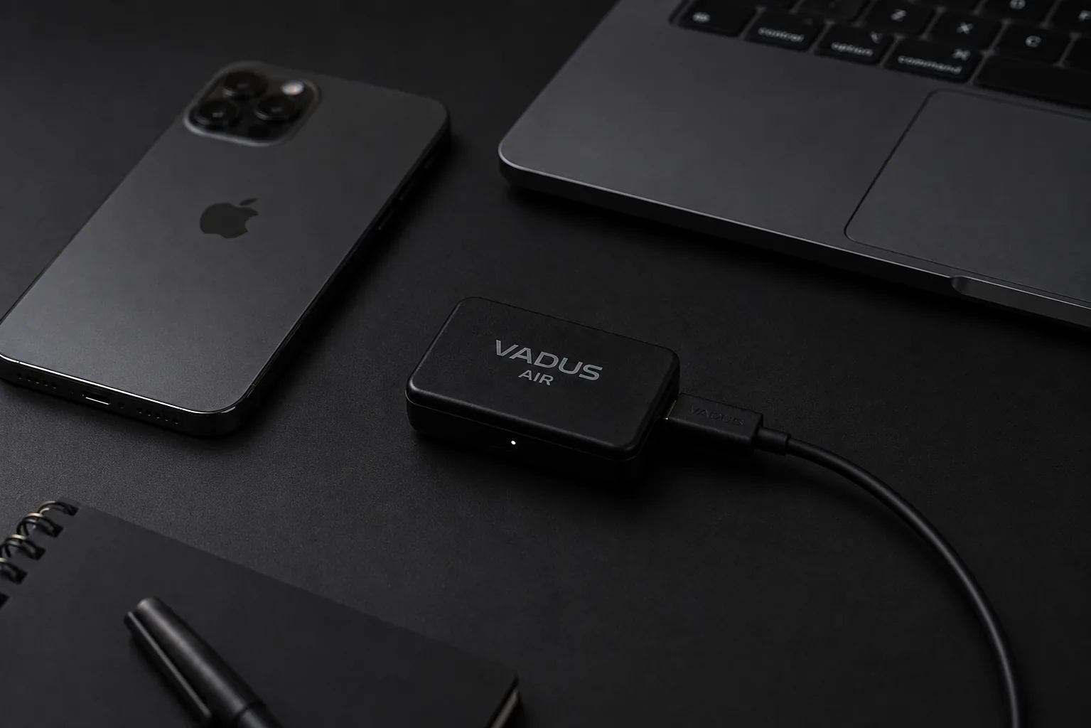Vadus Air pe un birou, lângă un telefon și un laptop, cu cablul USB-C montat.